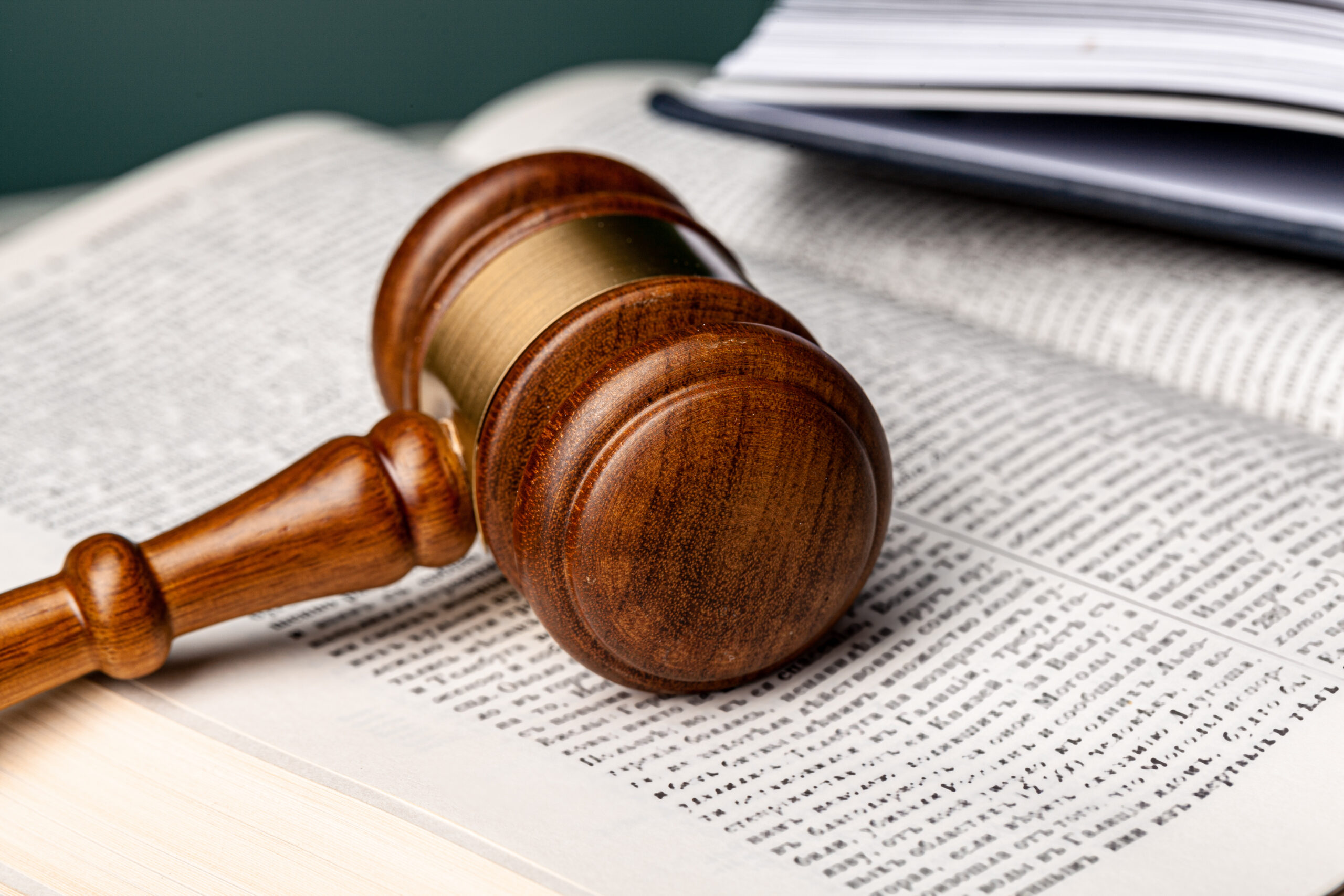 Marteau de juge en bois posé sur un livre de droit ouvert, symbole de la justice et de la législation