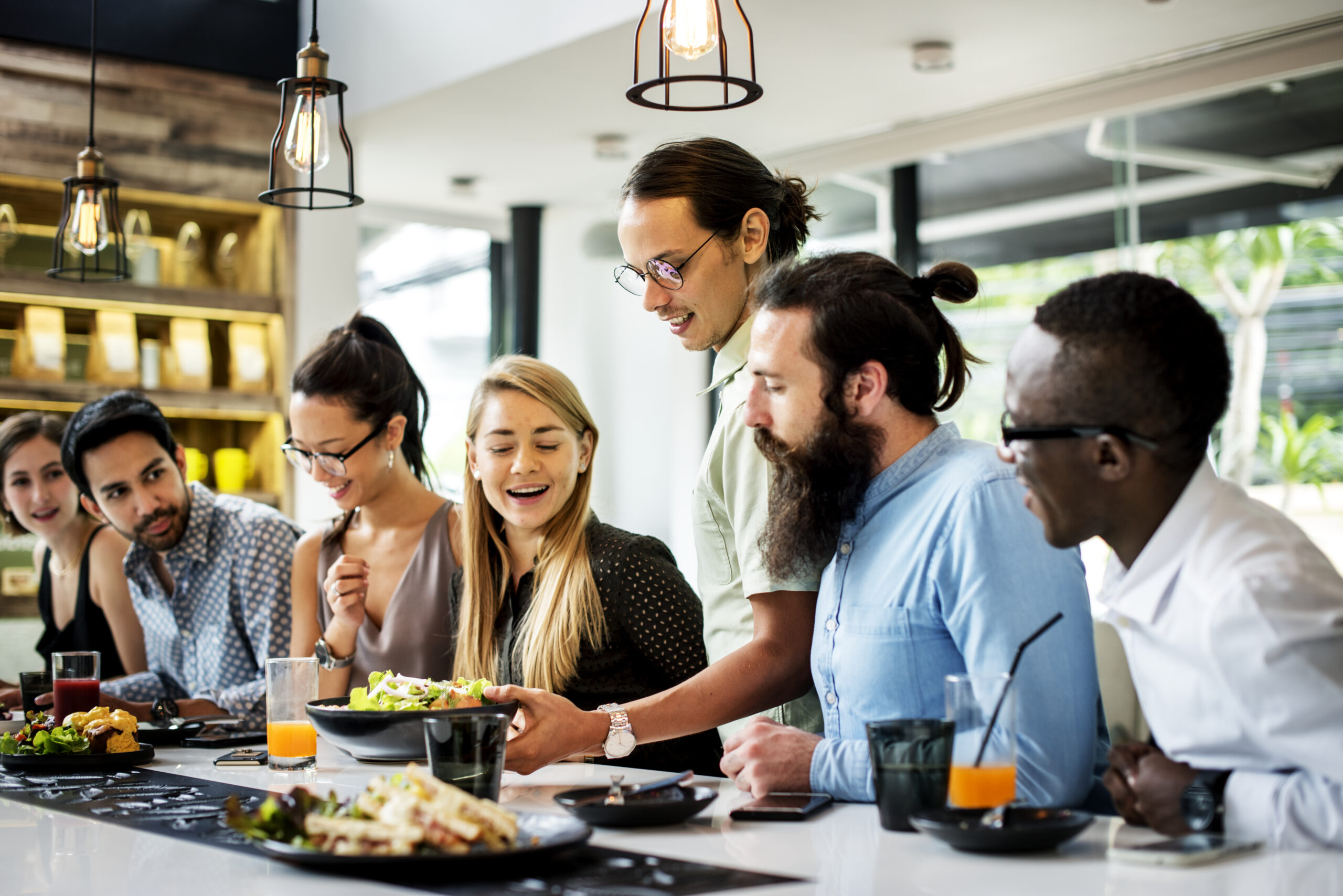 Groupe d’amis ou de collègues réuni autour d’un repas dans un restaurant.